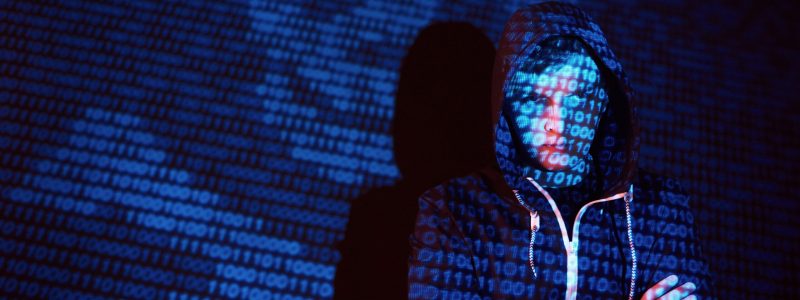 Cyber attack with unrecognizable hooded hacker using virtual reality, digital glitch effect.