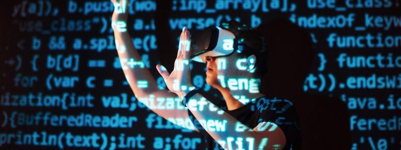 Double exposure of a caucasian man and Virtual reality VR headset is presumably a gamer or a hacker cracking the code into a secure network or server, with lines of code