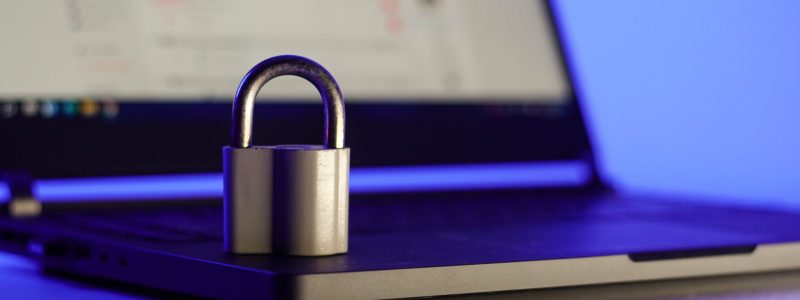 Locked metal padlock on a laptop keyboard over blue background. Cyber security, antivirus software concept.